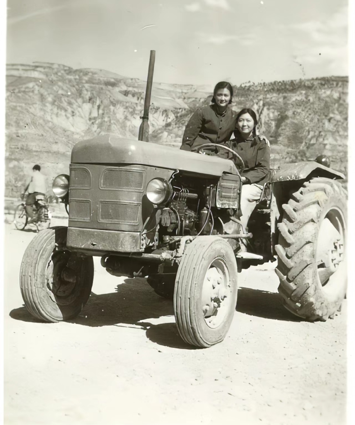 于东方红拖拉机驾驶位上,她们一个正在驾驶,一个站在边上