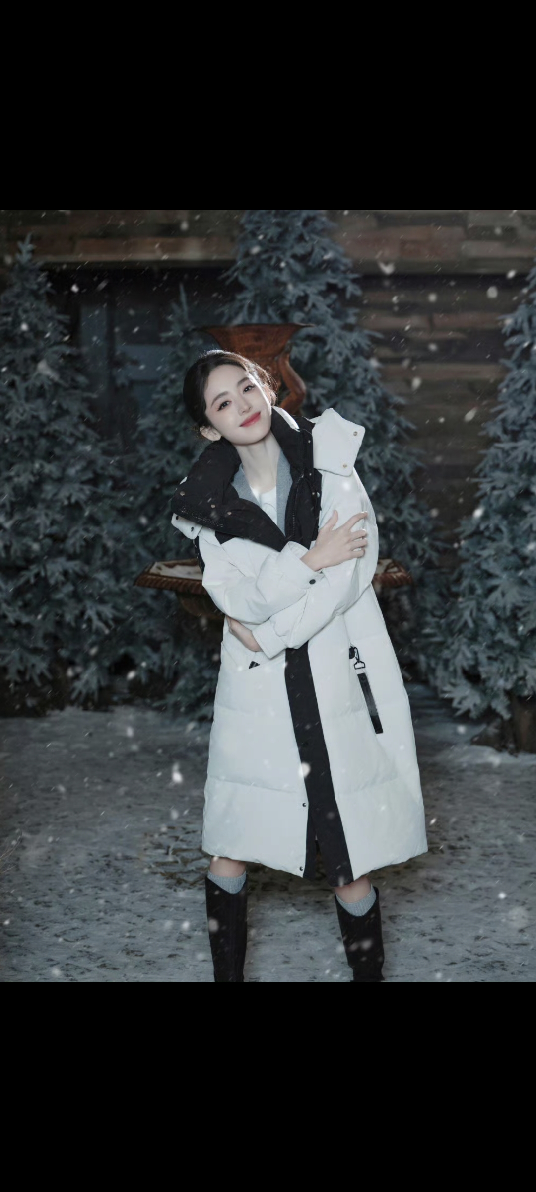 白色长款羽绒服,内搭灰色毛衣,配黑色短裙和长靴,时尚帅气