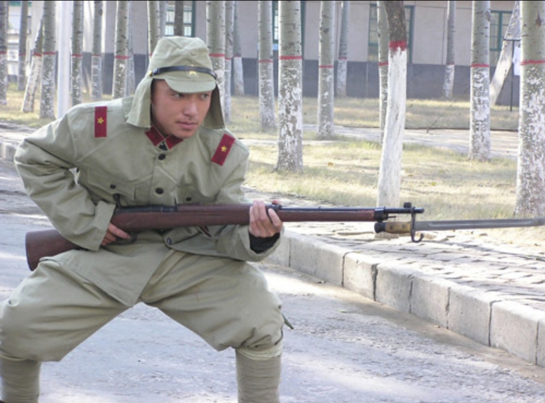 在院里,一名日本兵正持枪仔细排查,院里一处堆柴火