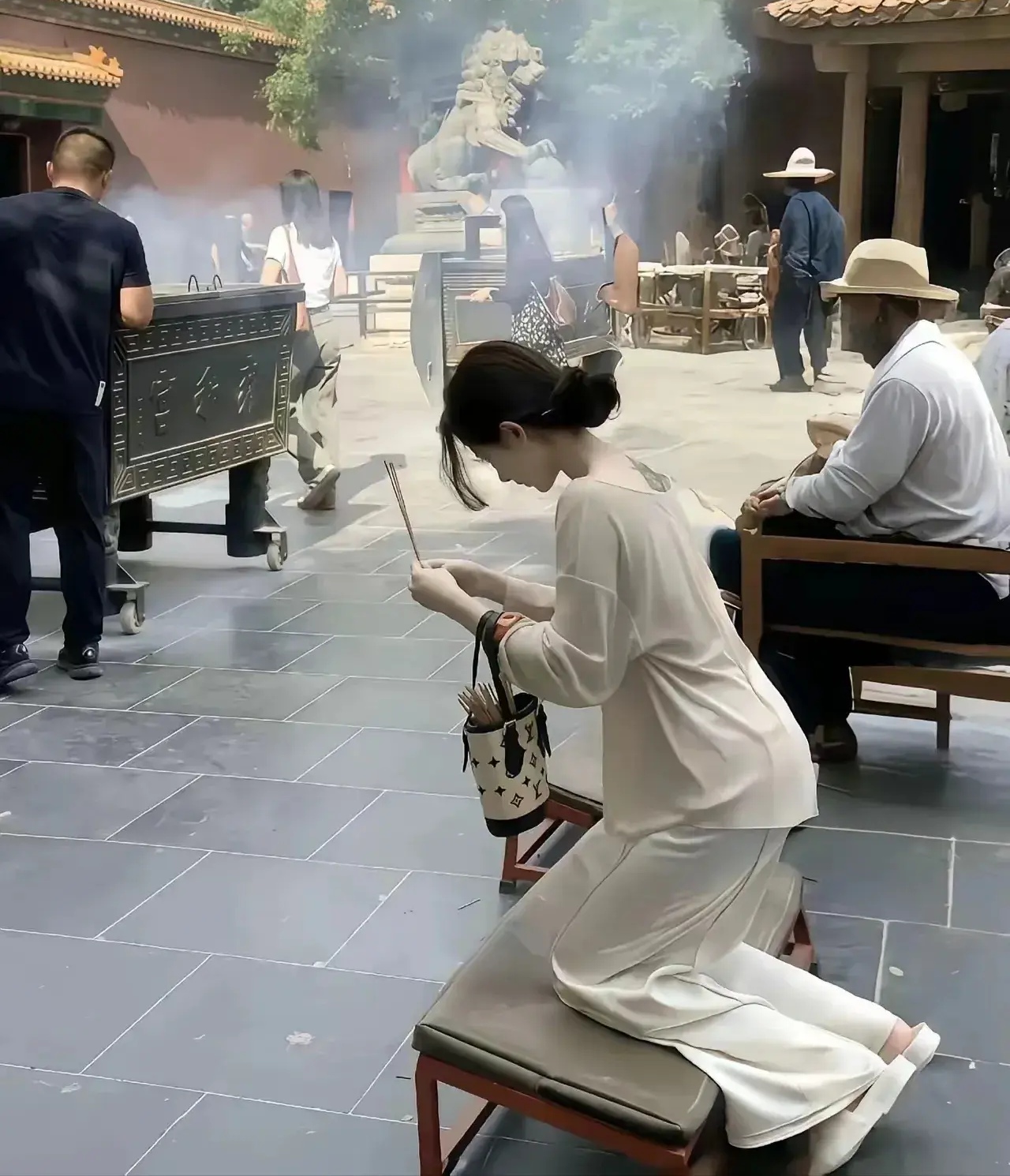 一位年轻貌美的女子正在求仙拜佛,皮肤白皙,身材苗条,手里提着一个