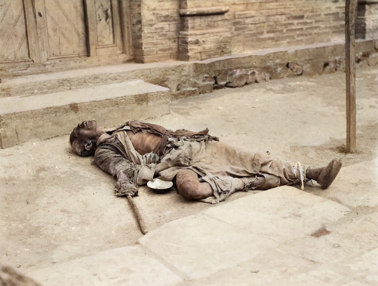 一名老年乞丐躺在路边,好像睡着了一样