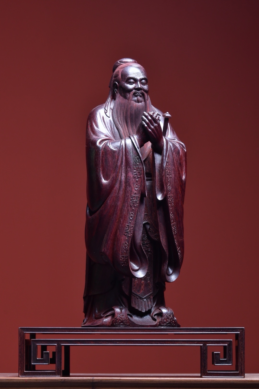 孔子束发髻,着儒服,眉目生动传神,稳重慈祥,双手交叠行礼,气宇谦和