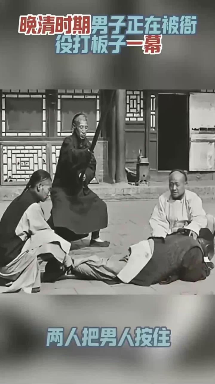 清末时期,男子被衙役打板子一幕,两人把男人按住另一人举起大板