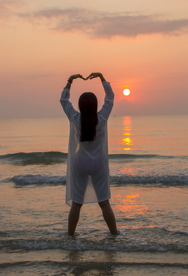 碧波轻拥海之涯, 美女如诗映晚霞. 秀发随风舞翩跹, 眼眸深邃映浪花