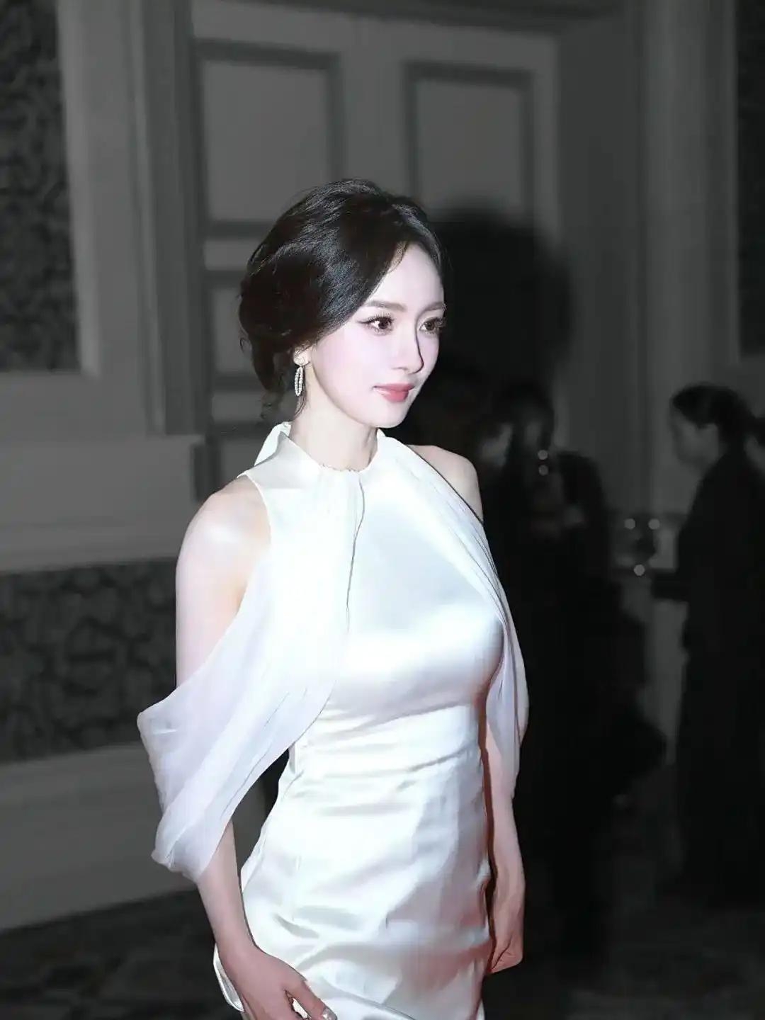 杨幂穿着一身白色裙子挂脖的设计把她好看的肩颈露了出来缎面的材质