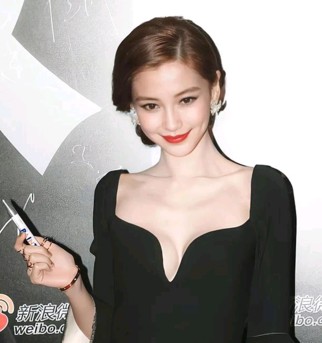 杨颖女明星,她身着一袭黑色深v礼服,优雅地站在背景板前