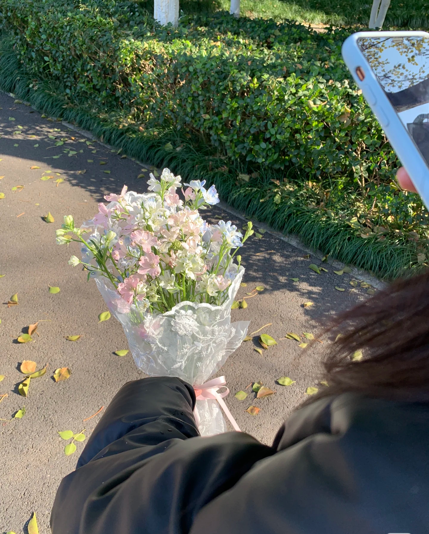 她手里捧着一束粉色的花,阳光正好洒下来,温暖又柔和