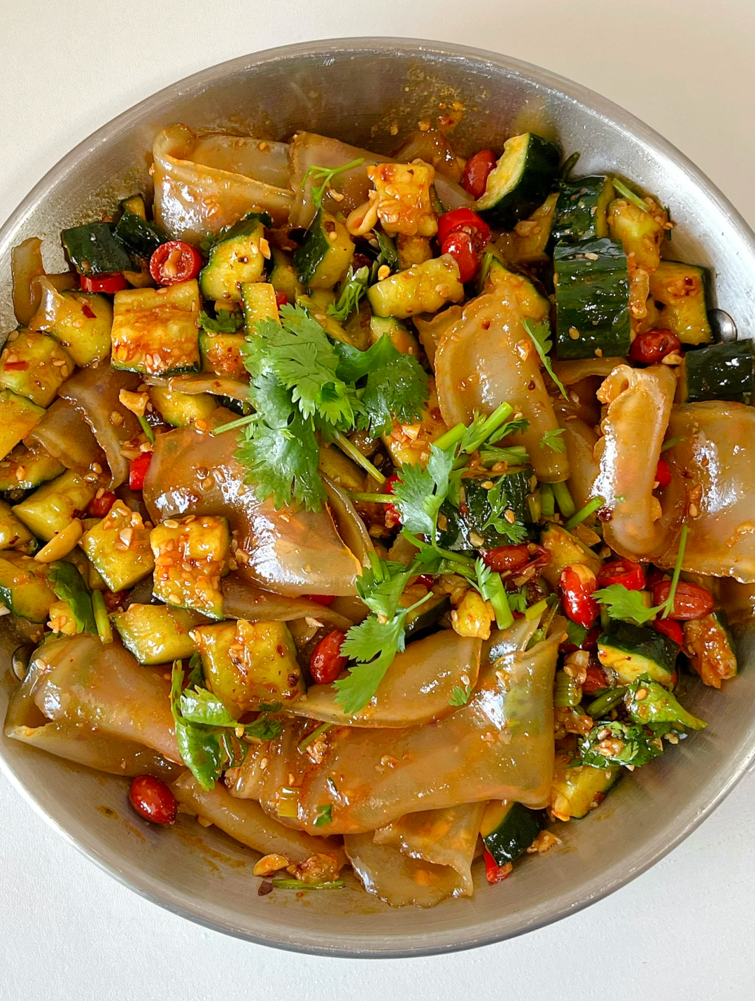 凉皮,香香辣辣的,盘中加入粉丝和黄瓜,撒上花生米香菜,倒入酱汁搅匀