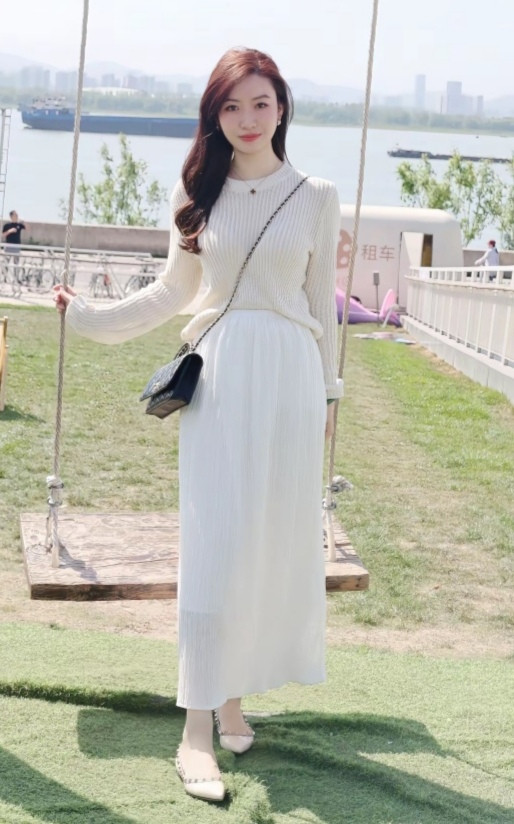 脚踩浅米色尖头平底鞋,精致小巧.斜挎黑色链条包,增添时尚感