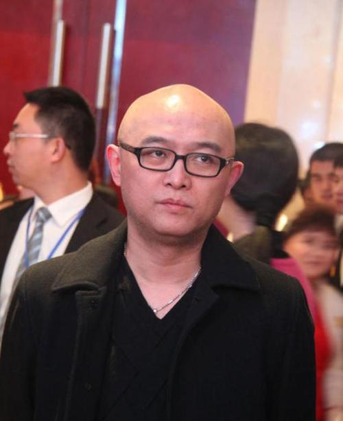 光头,黑框眼镜,形象极具记忆点,招牌式的微笑温暖亲和