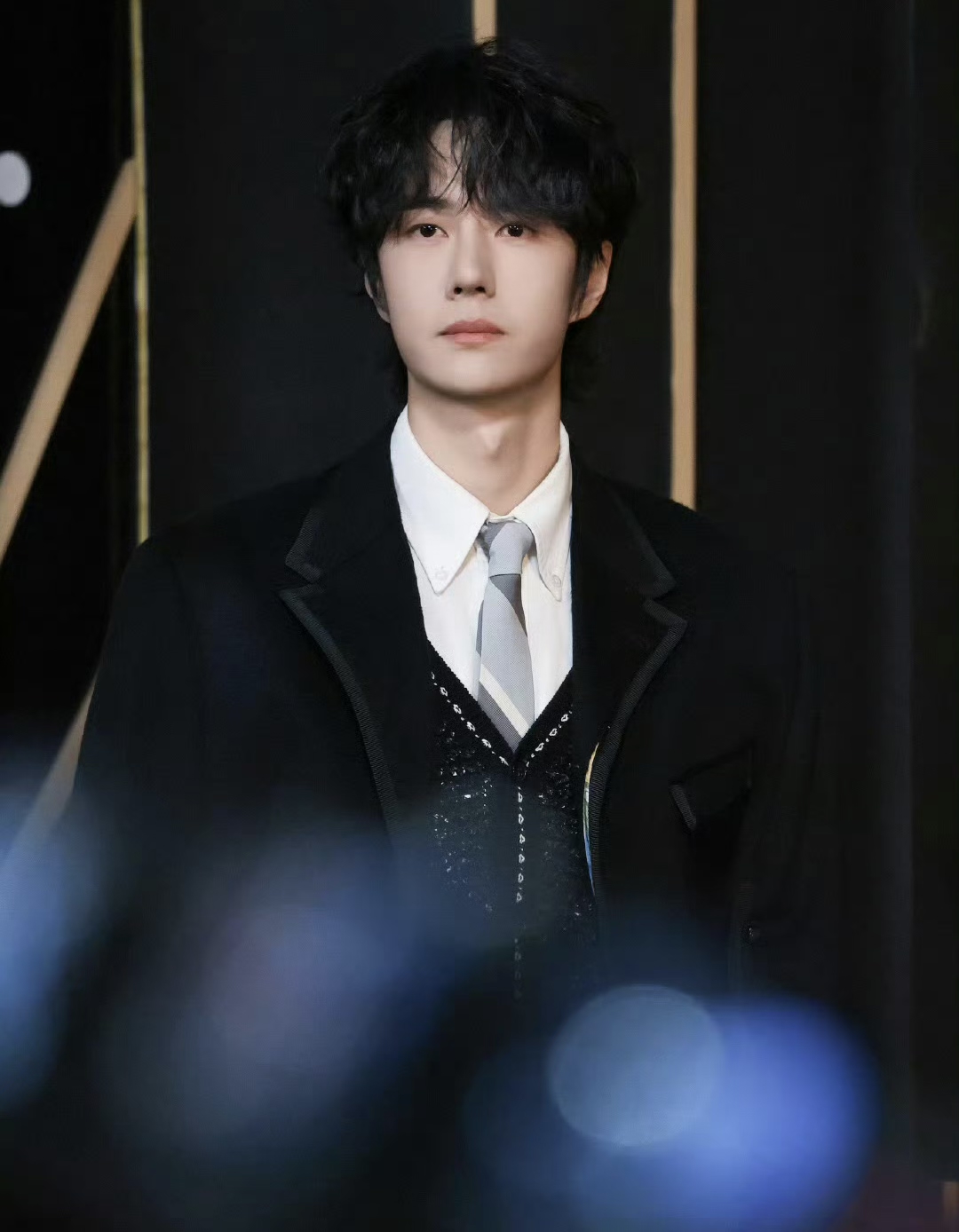 王一博身着黑色披风燕尾服参加微博之夜红毯活动,卷毛造型犹如"