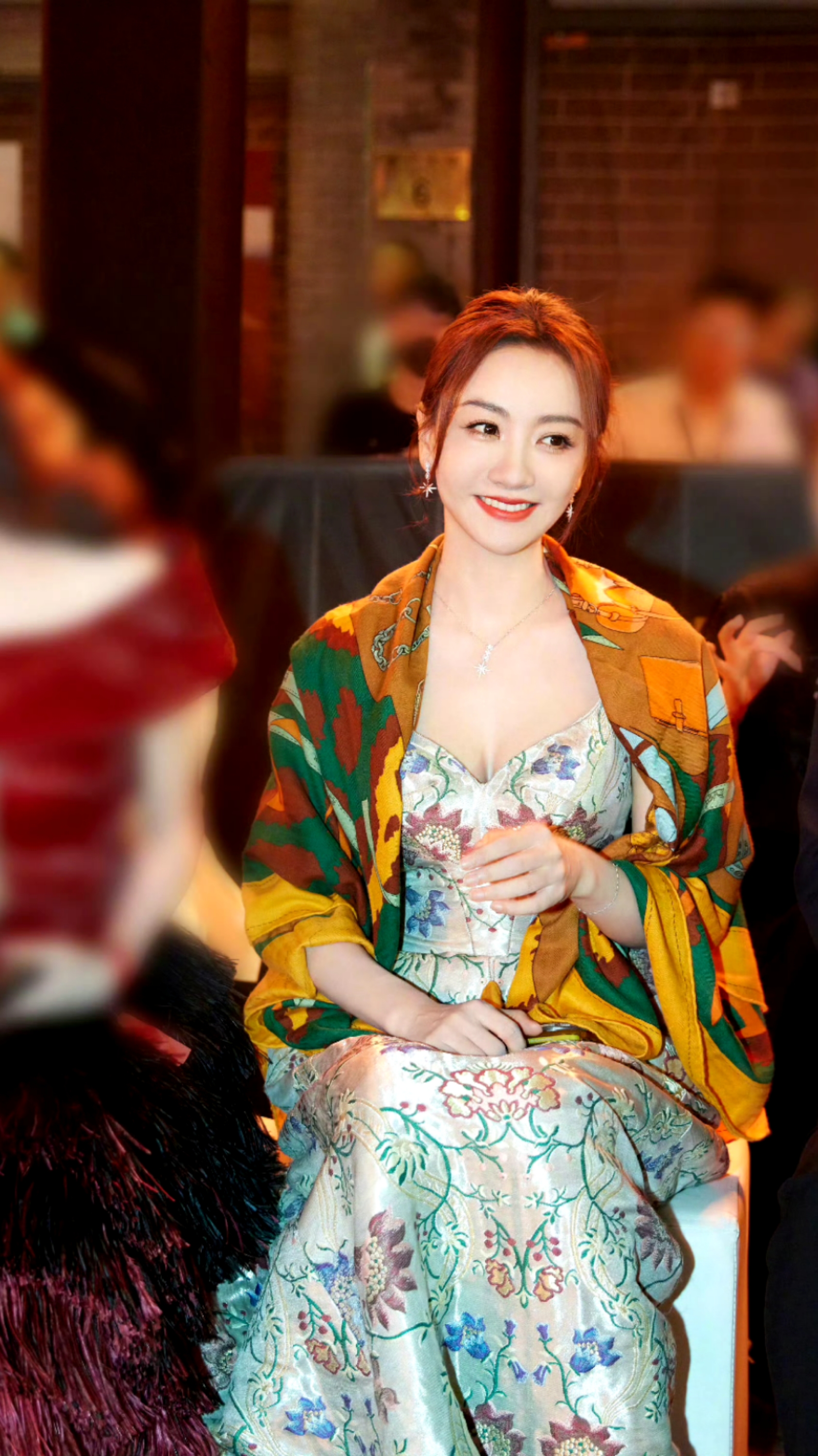 杨蓉身穿一条浅色系的连衣裙,裙身布满色彩丰富的花卉刺绣图案,精致