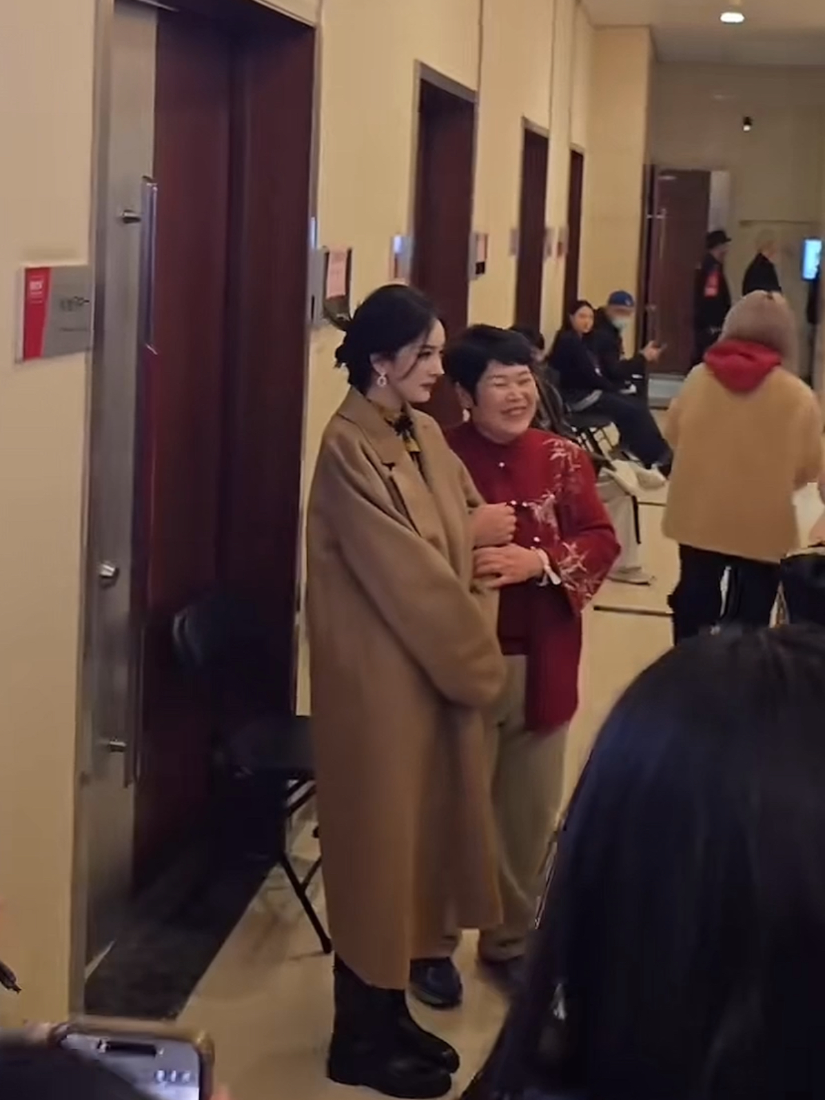 杨幂穿着大地色的大衣妆容发型都很精致房主任看到后一边搂着杨 