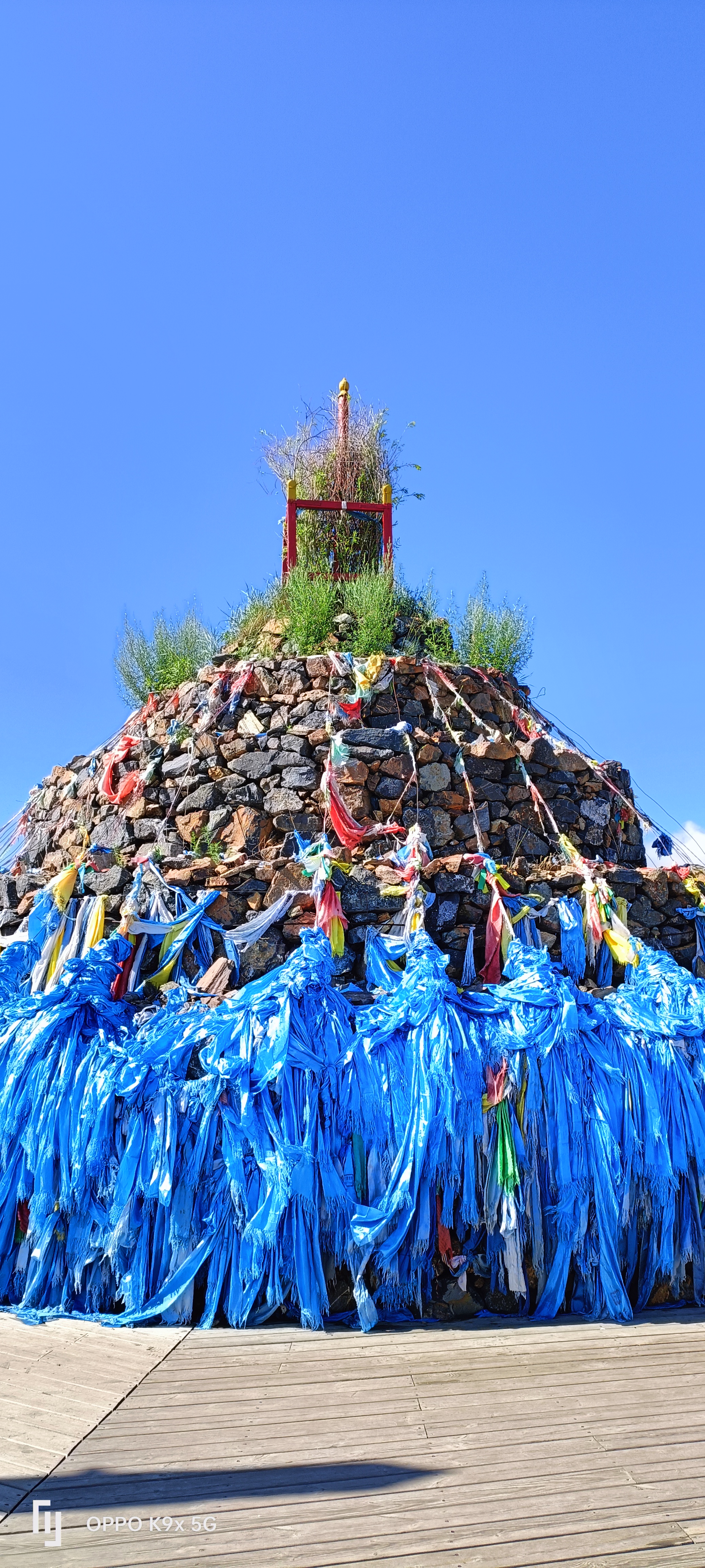 呼伦贝尔草原上的敖包,是石头堆成的圆疙瘩,顶上插着彩色经幡,风一吹