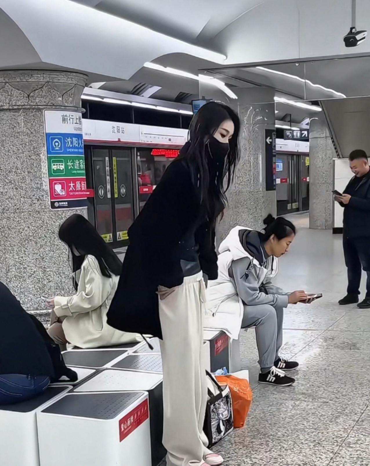 在地铁站里,一位穿了打底黑丝袜又套着长裤的女生,很快把长裤脱了下来