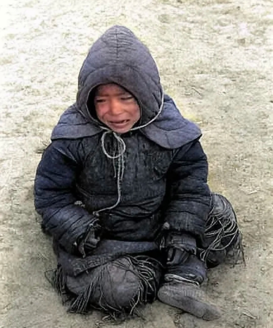 一个逃荒的小男孩坐在地上哭泣,他或许是被父母抛弃了,或许是饿的!