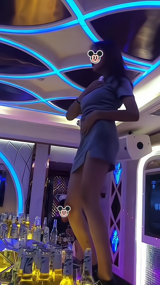 一女子喝醉酒后站在桌子上跳舞,其老公低头看手机,没有搭理她