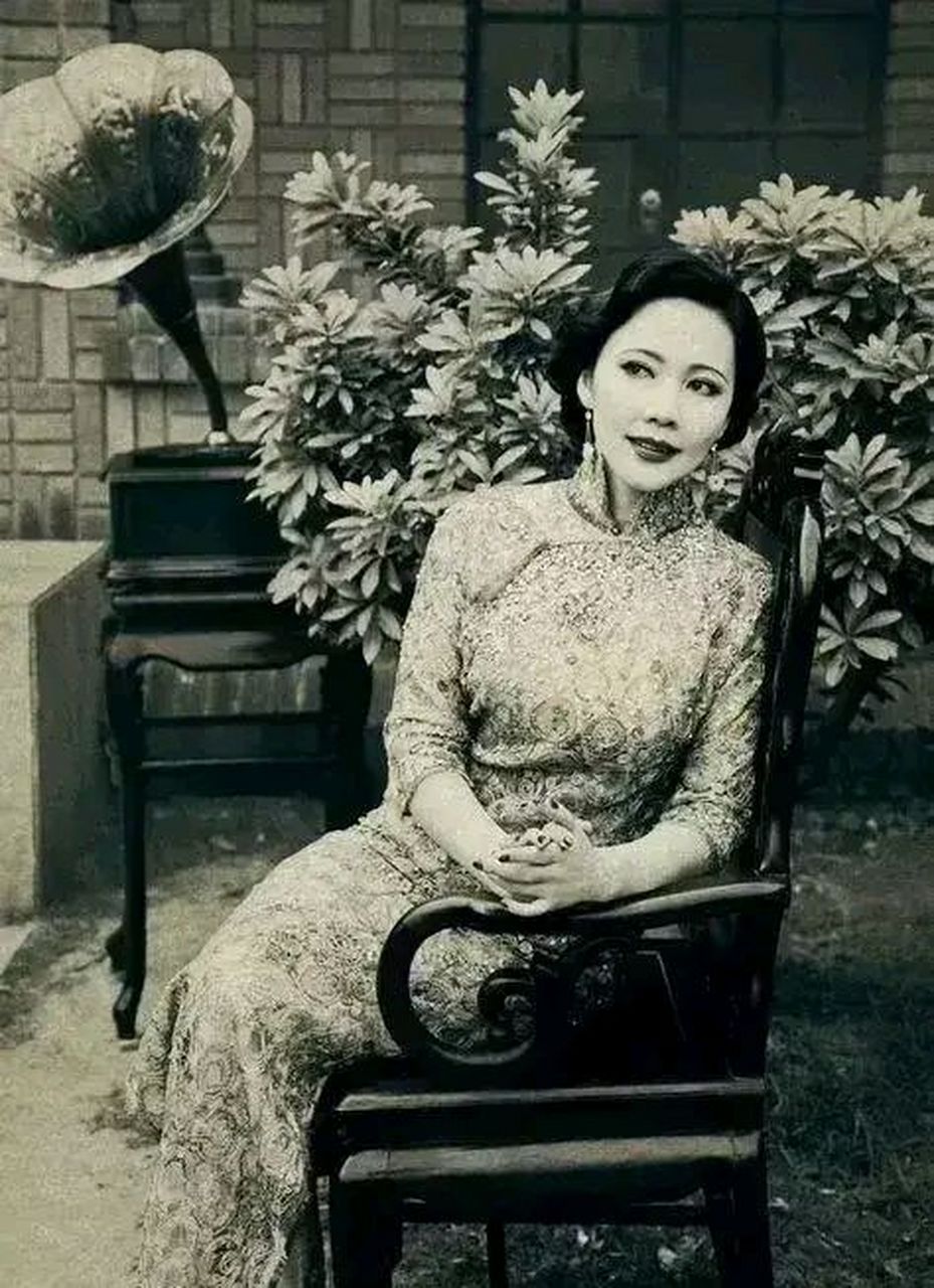 民国时期,一位穿着旗袍的富家太太坐在自家庭院的椅子上留影,这位女子