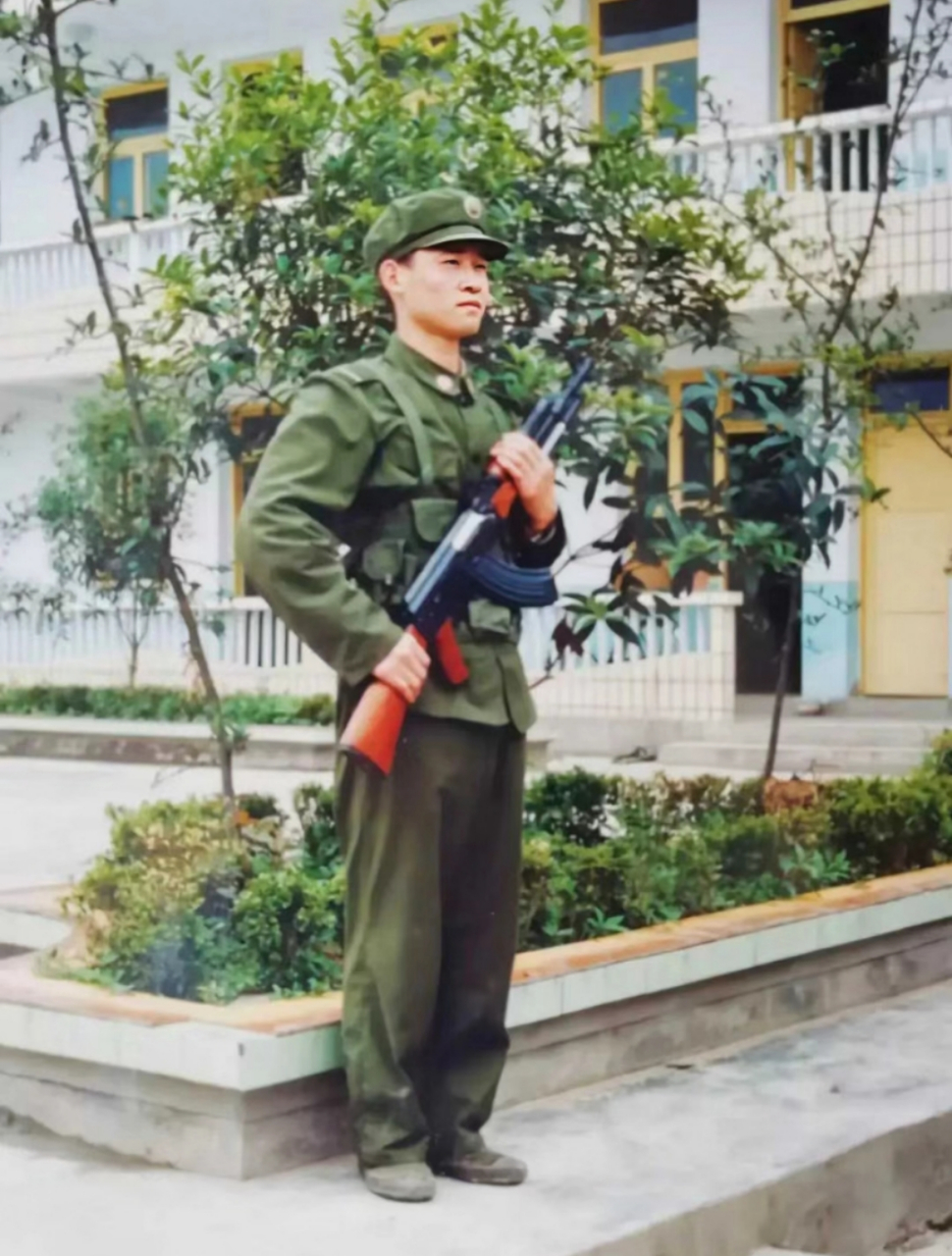 1986年,四川省成都市,某部队院内,一名穿着六五式军装,手持56式冲锋枪
