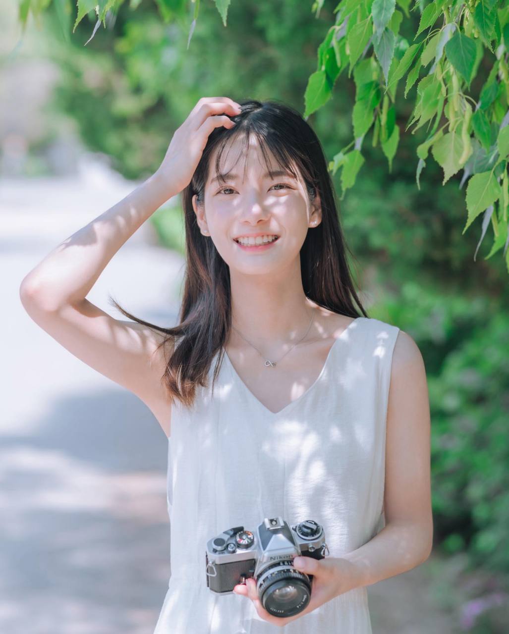 阳光透过树叶缝隙投下来,照在了姑娘微笑的清秀的脸庞上.