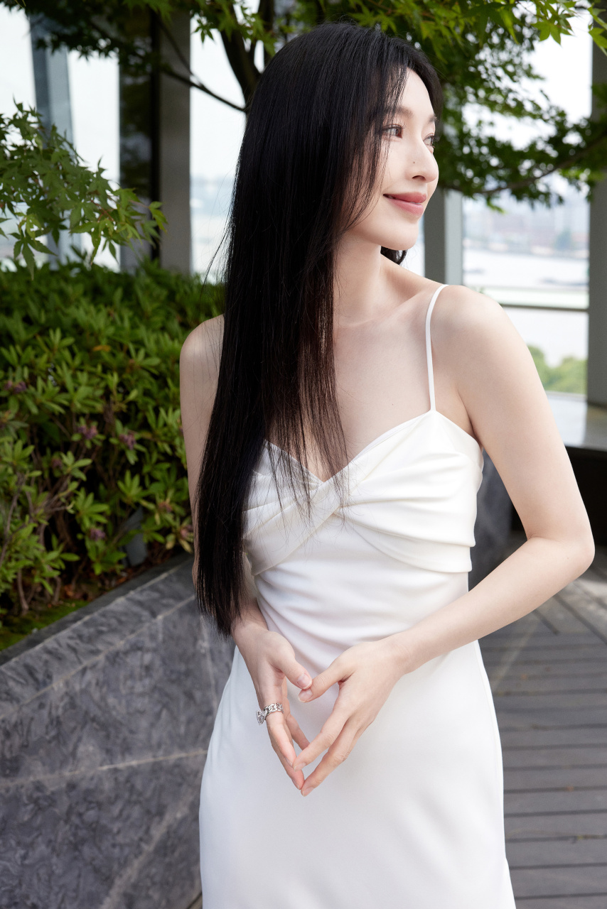 张俪着抹胸吊带白裙,展灵动之姿.