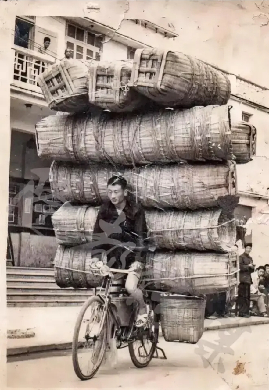 这是70年代,一个载着货物赶集的年轻人,照片中的他正在展示高超的车技