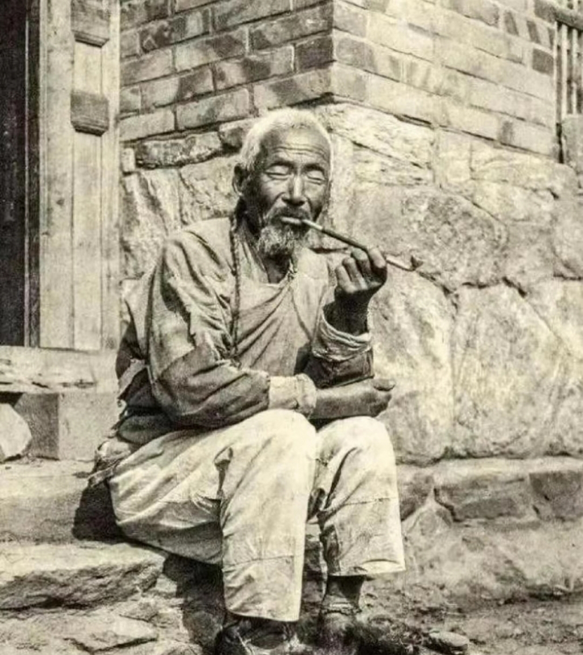 晚清时期,坐在家门口吸旱烟的老人,他穿着朴素,显然不是富裕阶层!