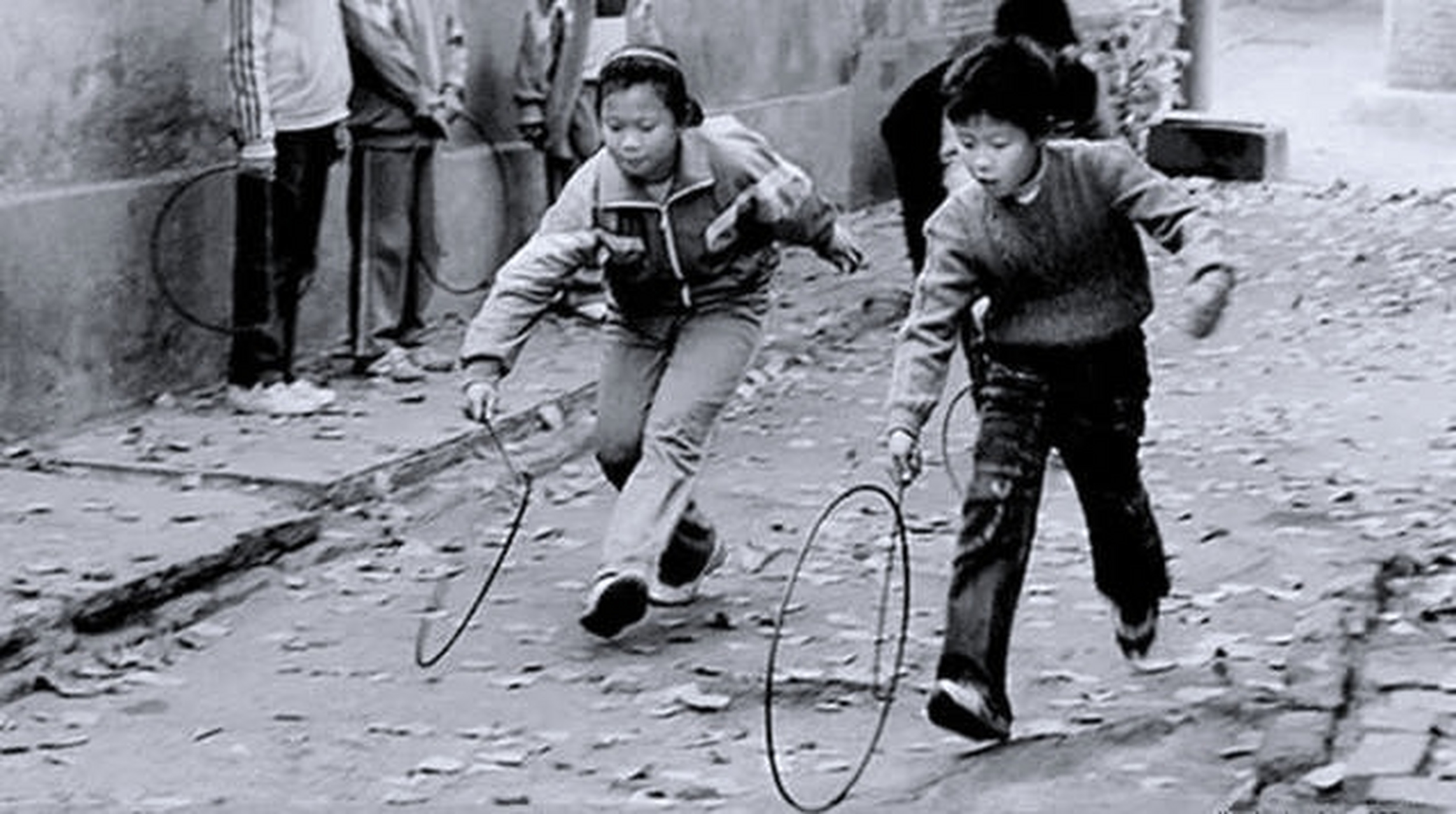 游戏玩法是手捏顶头是"u"字形的铁棍或铁丝,推一个直径66厘米左右的黑