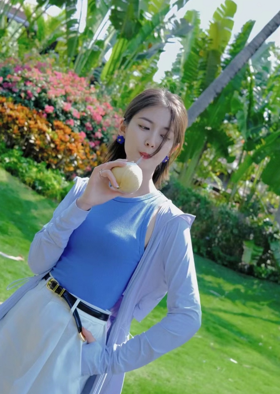 陈钰琪喝着椰汁开心拍照,她身穿一套蓝色休闲装晒太阳呼吸新鲜空气