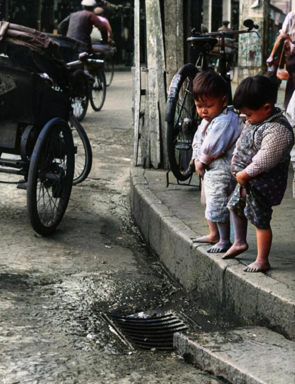 六十年代老照片,某城市街头,两个小孩站在街头小便,他们穿着开裆裤,这