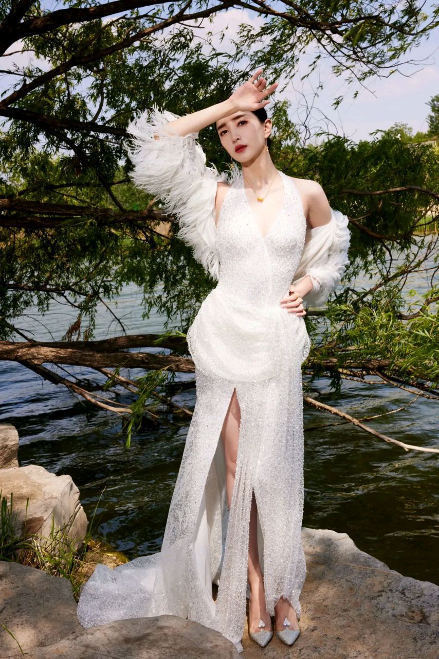 江疏影亮片蕾丝连衣裙,裙摆分叉设计深v露背,搭配羽毛披肩,在湖畔亭亭