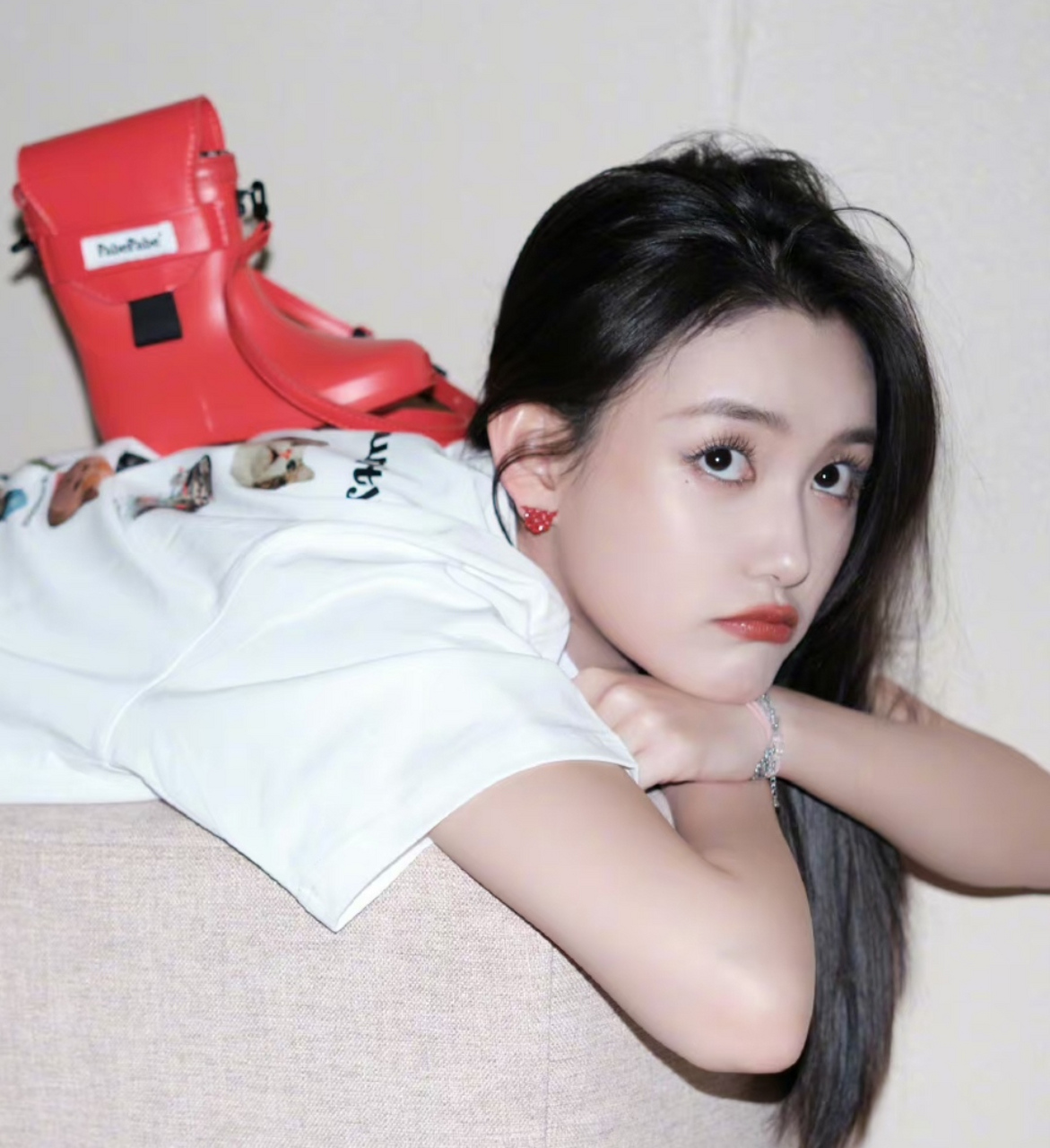 蒋依依在沙发背上凹造型,她的红色包包是靴子的形状,太时髦了