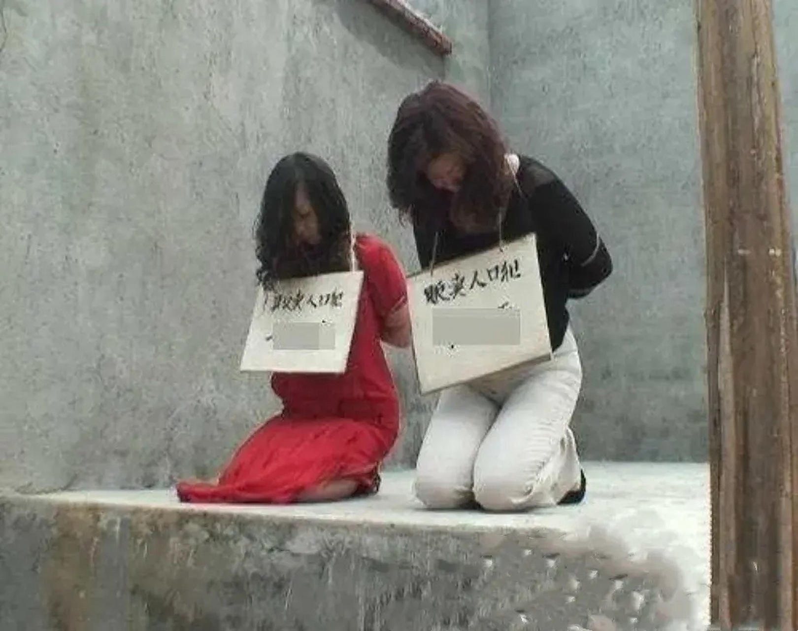 这张照片拍摄于于2003年,两个人贩子被五花大绑着,正跪在地上谢罪,这