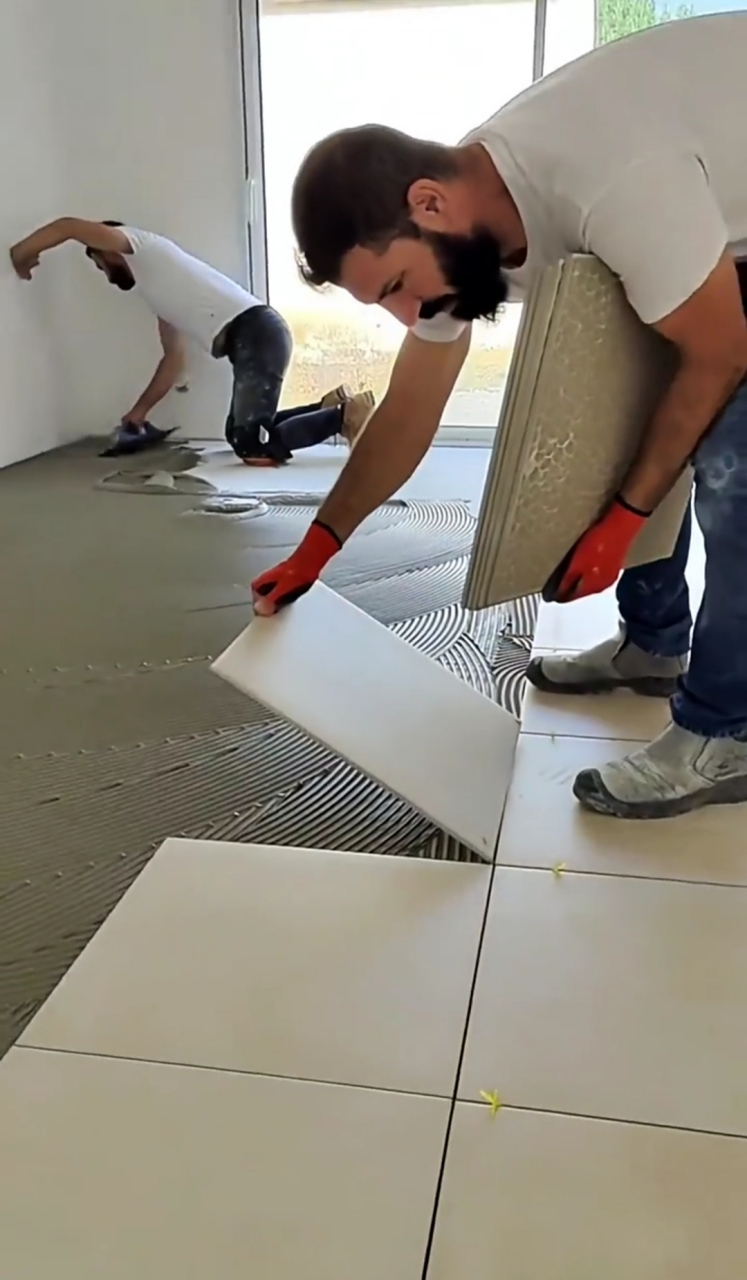 看老外这样铺地板砖,一个人把整间屋抹上灰,一个人就像铺地板一样一块