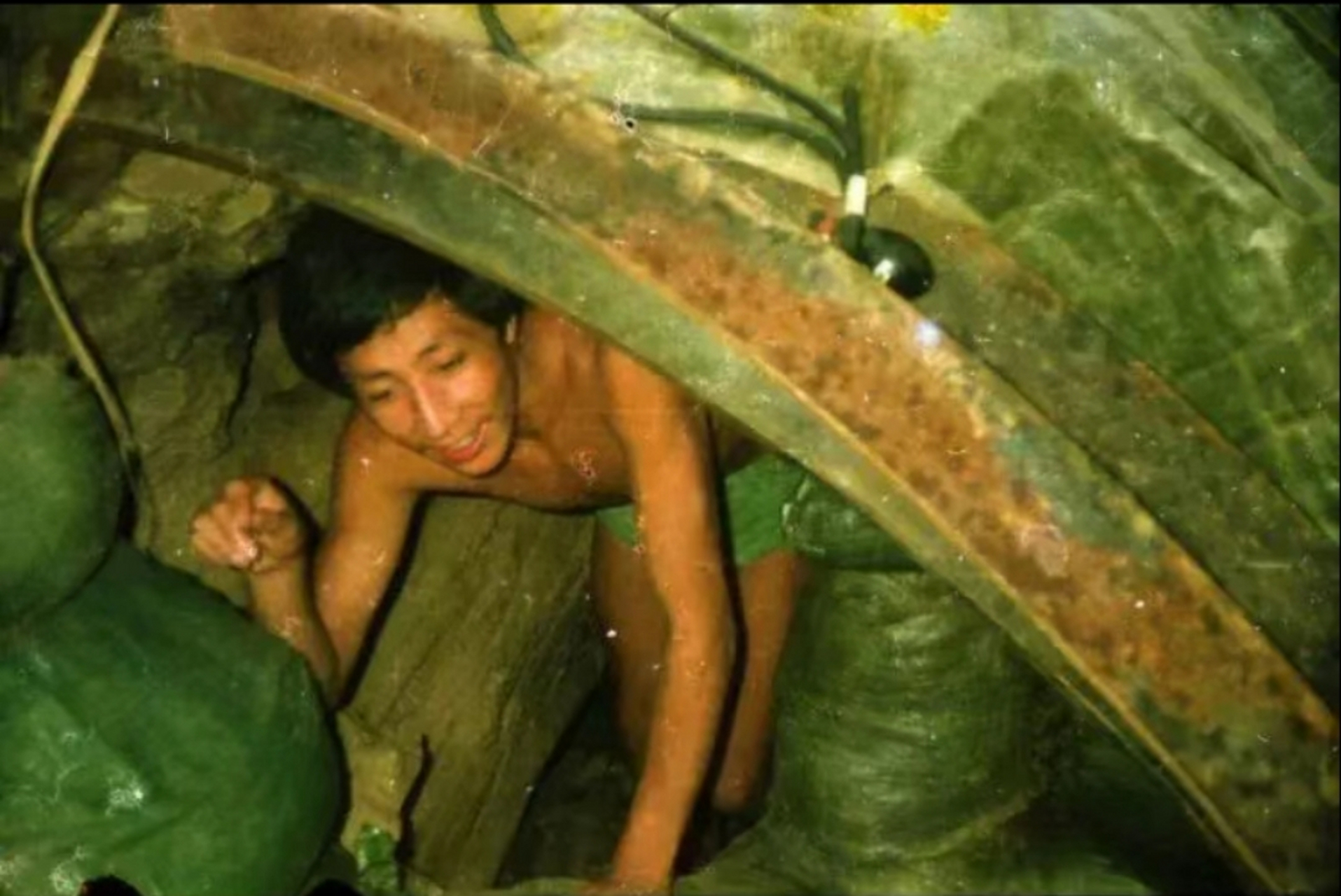 1986年,老山前线,一名解放军战士正在"猫耳洞"里弯腰行走.