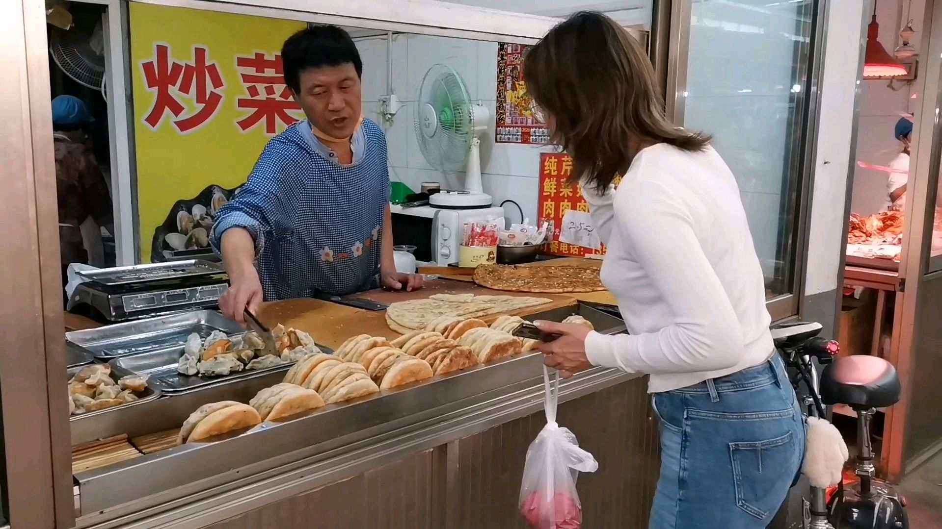 山东一个市场做带馅面食的摊位,肉用人工刀切,出锅就围上人买