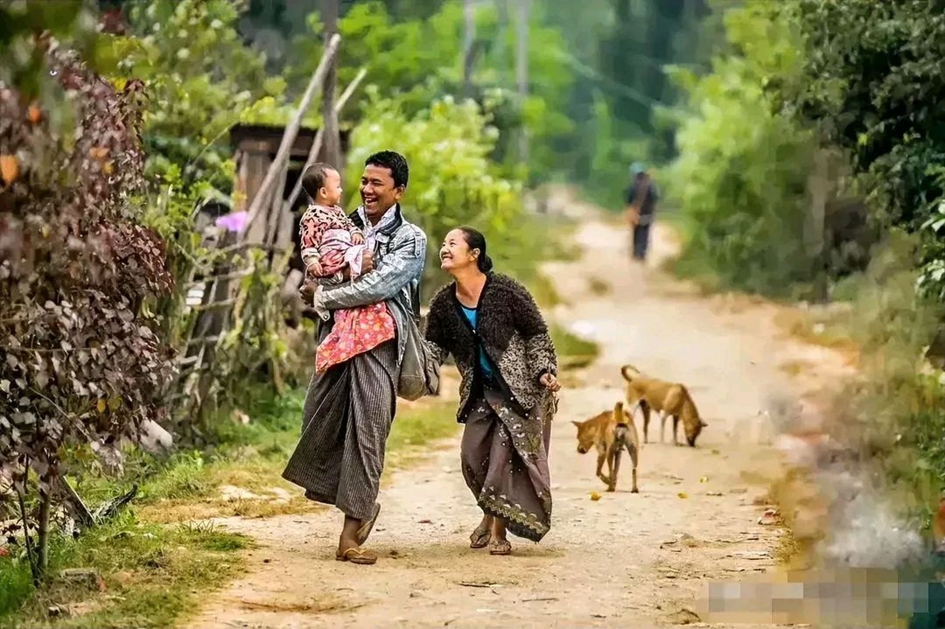 一条乡村的小路上,爸爸抱着孩子,妈妈跟在后面,爸爸笑容可掬,妈妈脸上