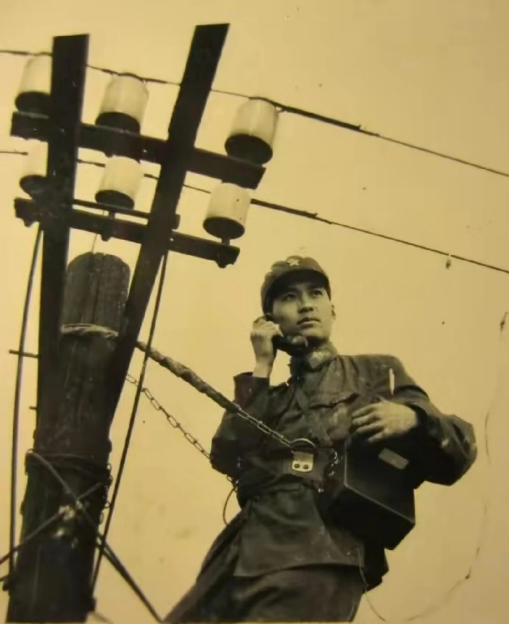 历史老照片,上世纪70年代,一名通信兵正在电线杆上测试线路.