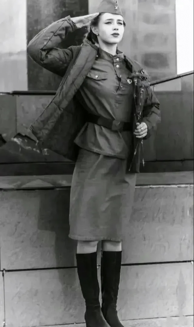 刚刚激战过的大街上,一名苏联女兵正在向经过的长官敬礼,随军记者拍下