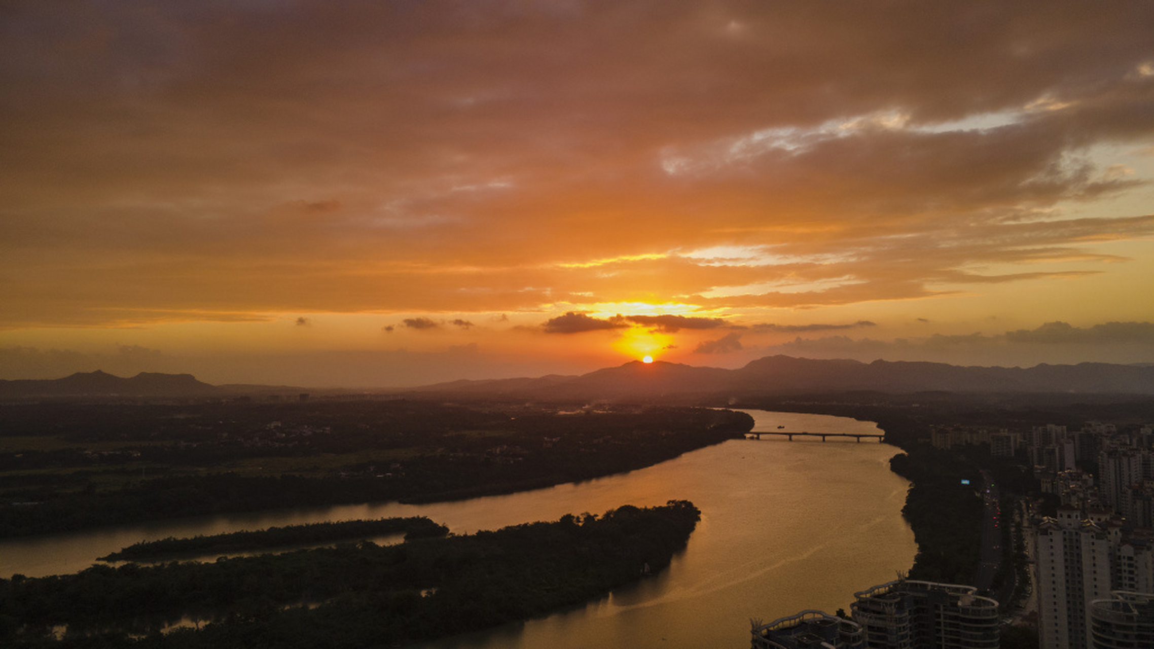 日暮时分,海南万泉河畔,太阳渐渐落下,将天边晕染成一片橘红,画面唯美
