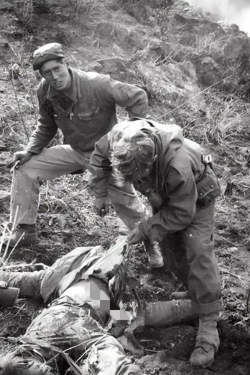 朝鲜战场上,一名牺牲的志愿军战士遗体躺在地上,两名美国士兵手拿匕首