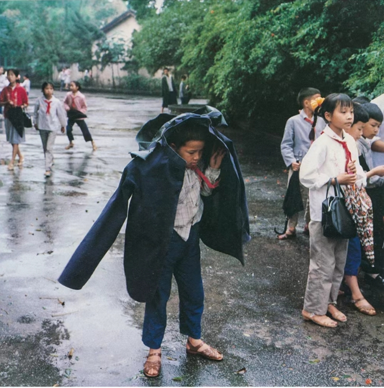 八十年代老照片,放学后,外面下着小雨,地面很滑,很泥泞,有的小学生拿