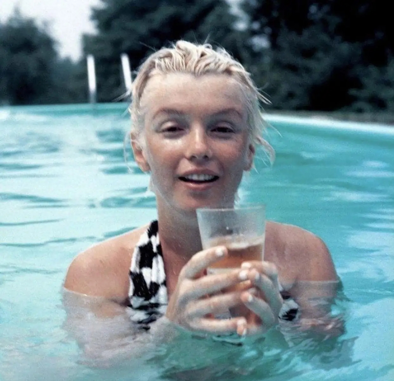 素颜时候的玛丽莲梦露,照片中梦露穿着吊带泳衣游泳,累了之后拿着被子