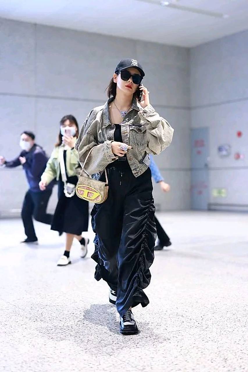 戚薇街拍,她穿了一件灰色的短款牛仔外套,内搭一件黑色小背心,搭配一