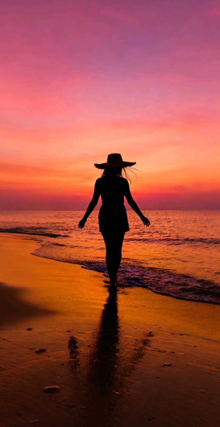 夕阳西下,一位戴著宽檐草帽的女性剪影,漫步