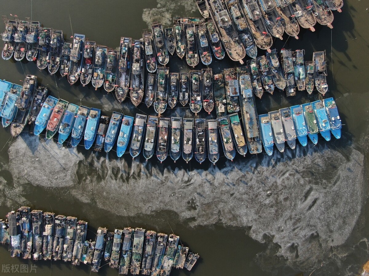 冬至到来,天津北塘渔港码头附近渔船周围结薄薄的一层冰