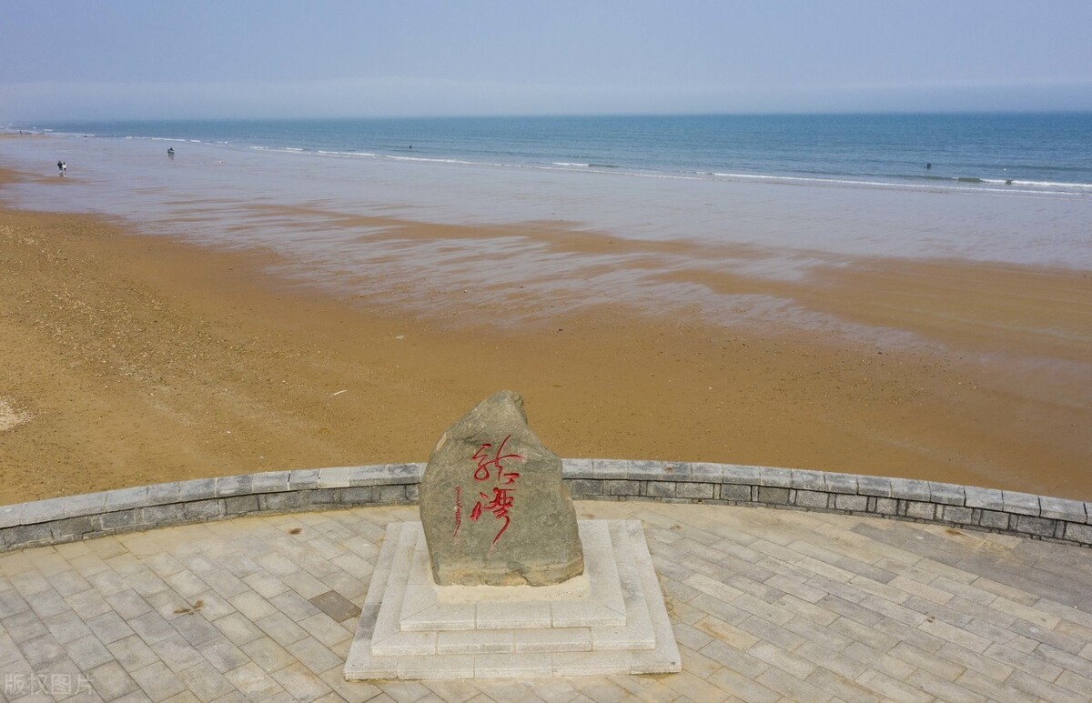 青岛西海岸新区龙湾海滨春光明媚,沙滩上的海水奔涌,层层叠浪