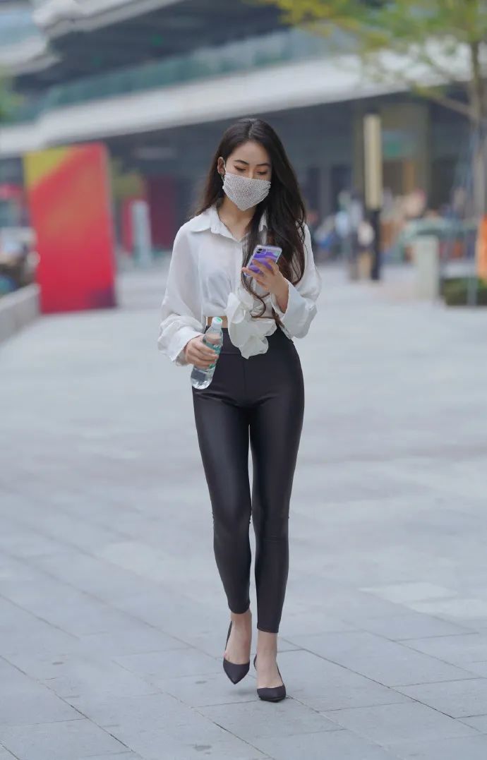 美女身穿白色上衣搭配黑色皮裤高跟鞋,穿出迷人身姿