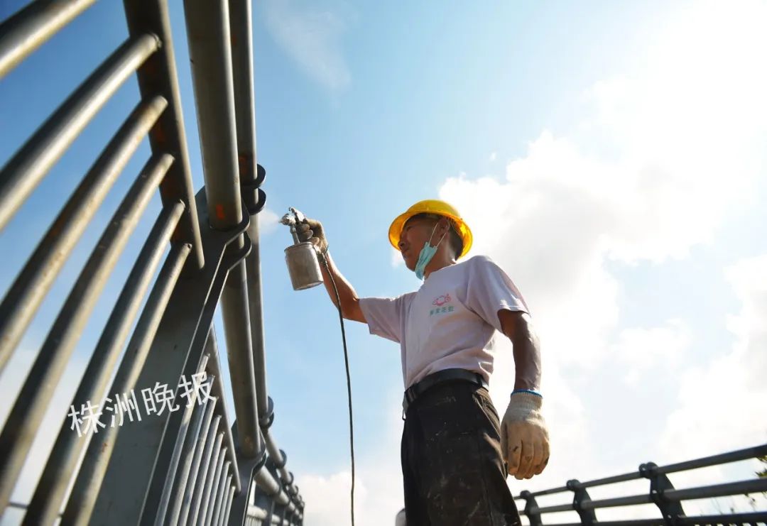 工人在给天桥的铁栏喷漆