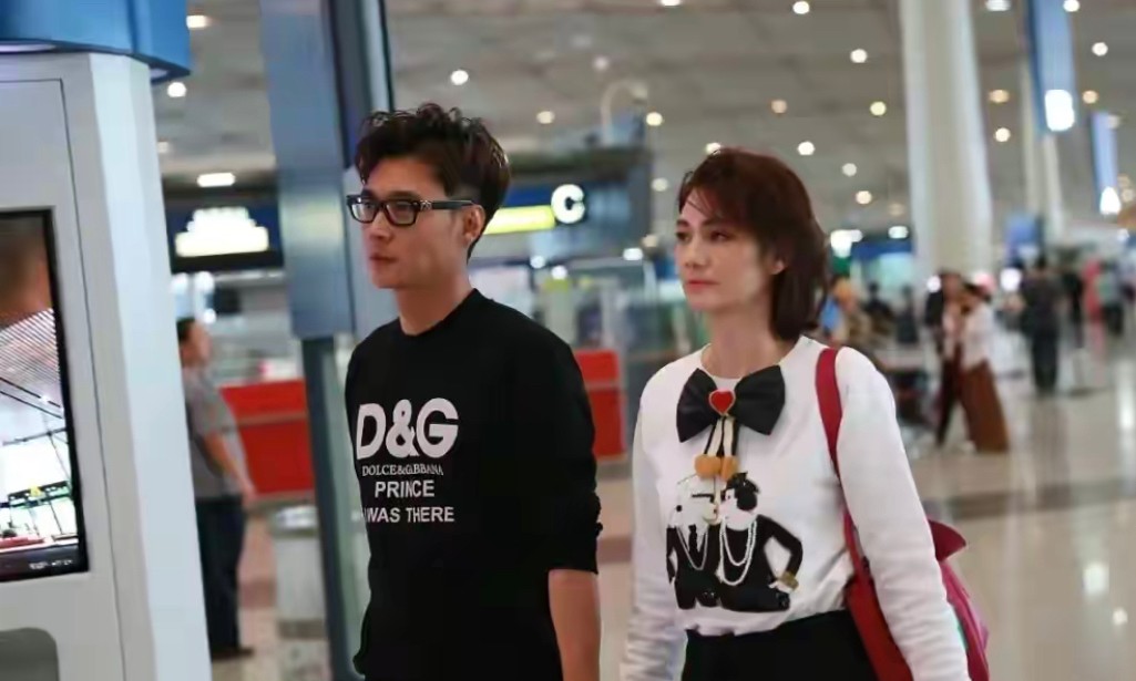 50岁洪欣和小10岁老公走机场,穿白上衣配短裙,衰老痕迹明显